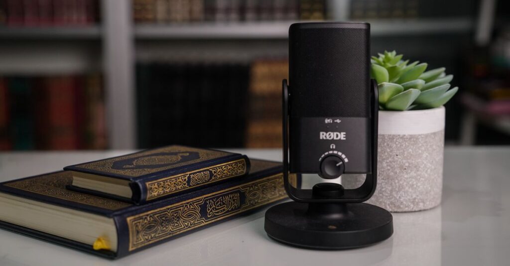 Close-up of books with a Røde microphone and succulent on a desk.